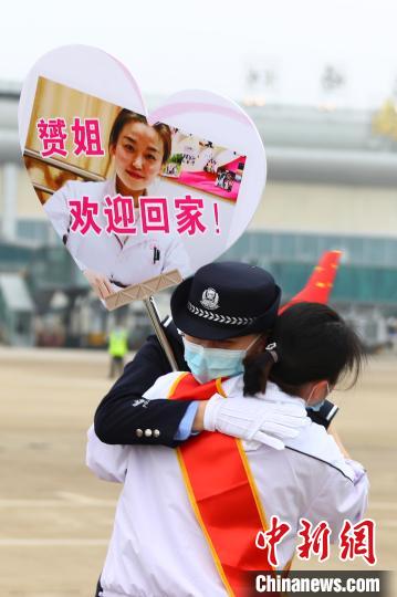 3月23日下午,一名医疗队队员与举着贴有自己照片牌子的民警妹妹相拥。 刘占昆 摄  369名队员凯旋!江西对口支援随州医疗防疫队返赣